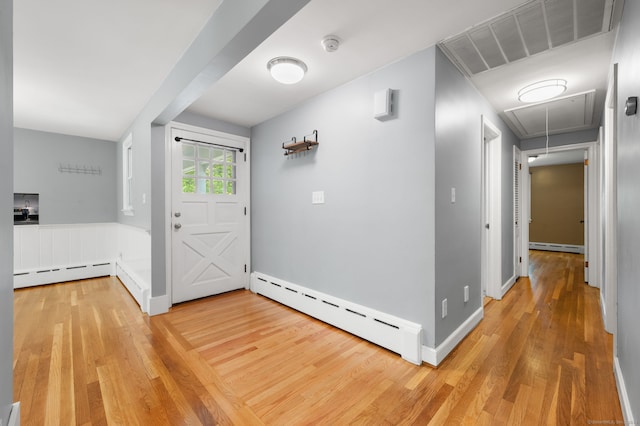 foyer entrance featuring a baseboard heating unit, light wood-type flooring, a baseboard radiator, and baseboards