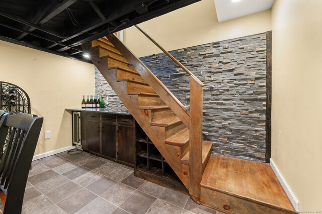 stairs with baseboards and a dry bar