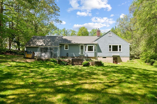 back of house with a chimney and a yard