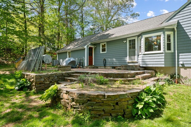 rear view of property with entry steps and a shingled roof