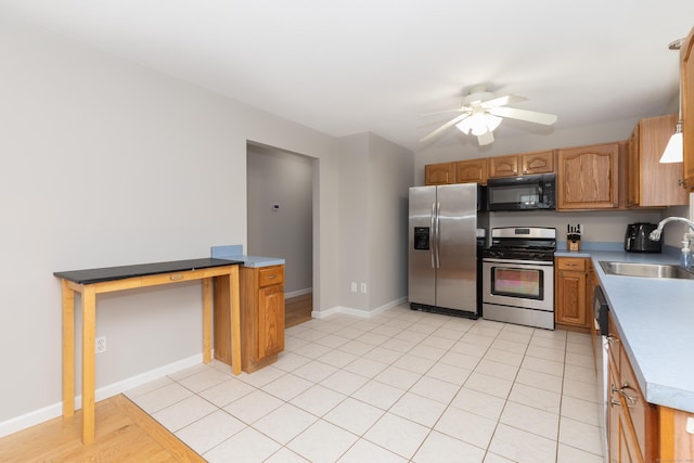 kitchen with appliances with stainless steel finishes, a sink, a ceiling fan, baseboards, and brown cabinets