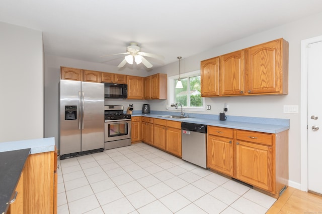 kitchen with stainless steel appliances, a sink, ceiling fan, hanging light fixtures, and light countertops