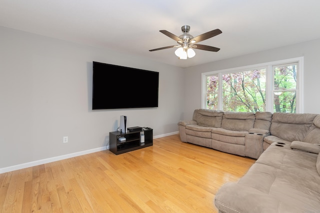 living room featuring a ceiling fan, baseboards, and light wood-style flooring