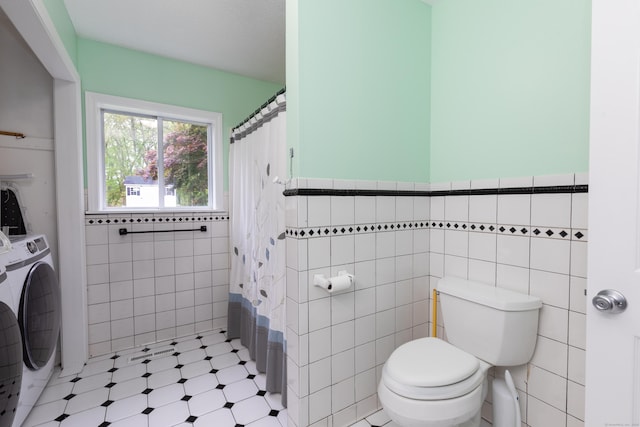 full bath with tile walls, washer / dryer, toilet, a wainscoted wall, and a shower with shower curtain