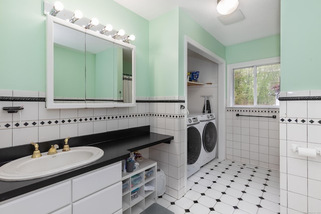 bathroom with independent washer and dryer, tile walls, wainscoting, vanity, and tile patterned floors