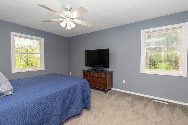 bedroom with light colored carpet, baseboards, and a ceiling fan