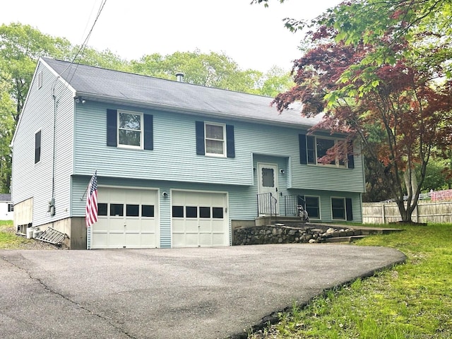 split foyer home with a garage, driveway, and fence