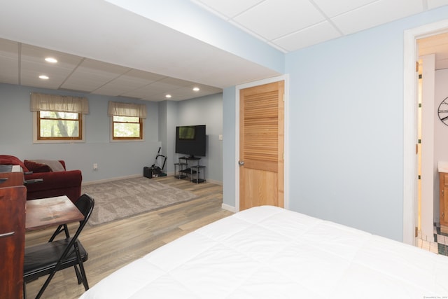 bedroom featuring wood finished floors, a drop ceiling, recessed lighting, and baseboards