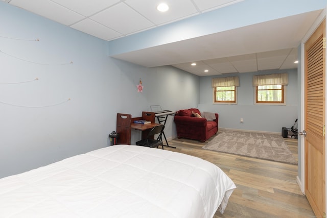 bedroom with a paneled ceiling, light wood-style floors, baseboards, and recessed lighting