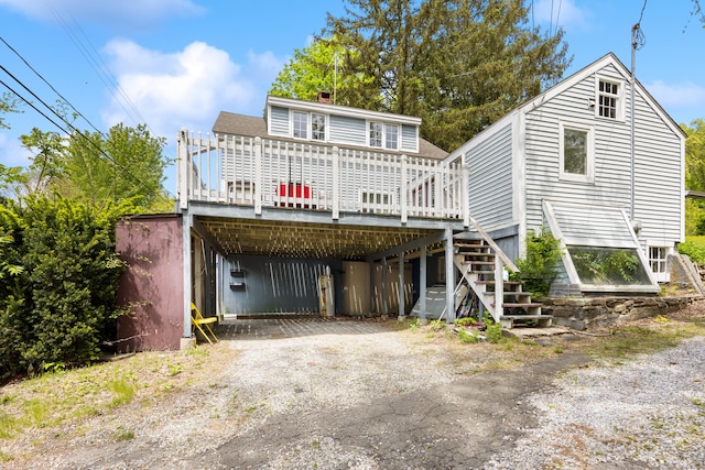 view of front facade featuring a deck, dirt driveway, a carport, a chimney, and stairway