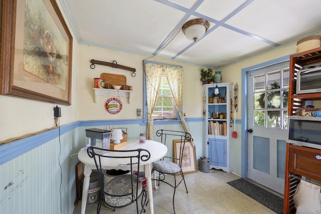 dining room with wainscoting, light flooring, and ornamental molding