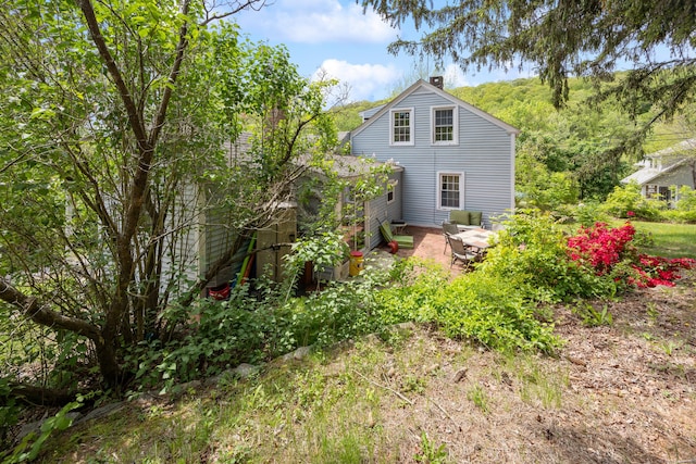 back of property with a chimney and a patio