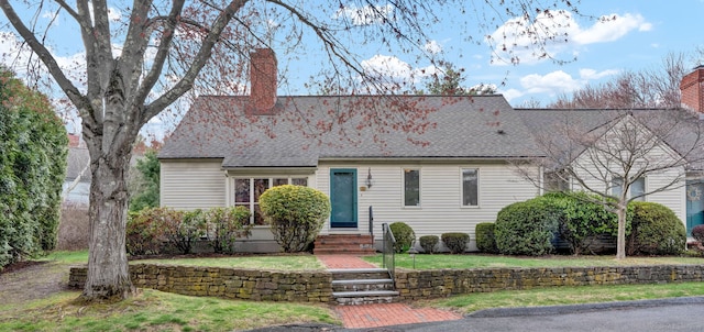cape cod home featuring a chimney, entry steps, a front yard, and roof with shingles