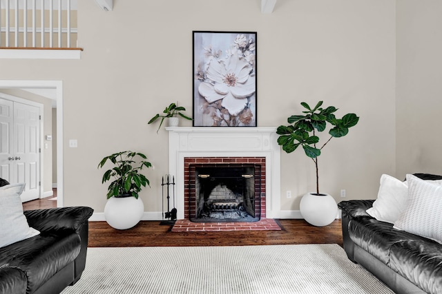 living room with wood finished floors, a brick fireplace, and baseboards