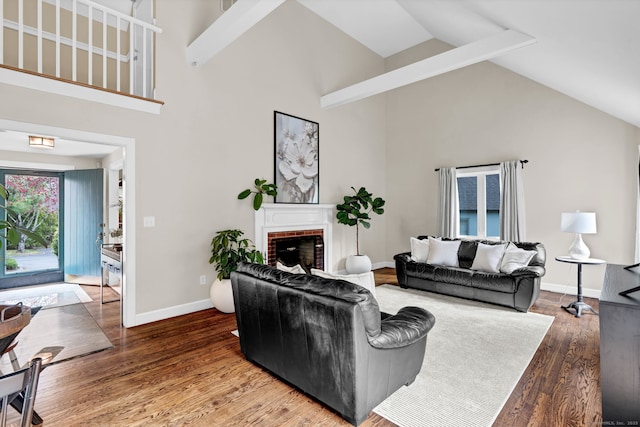 living area featuring high vaulted ceiling, wood finished floors, a fireplace, and baseboards