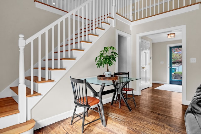 stairs with wood finished floors, baseboards, and a towering ceiling