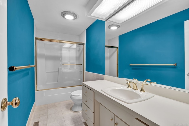 bathroom featuring toilet, vanity, tile patterned flooring, and combined bath / shower with glass door