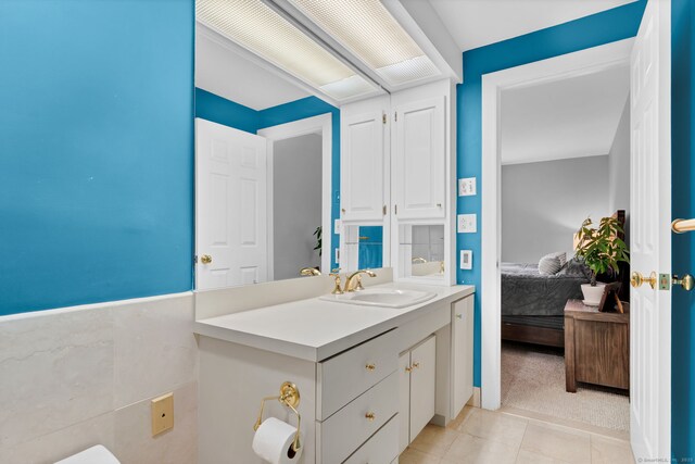 bathroom featuring ensuite bathroom, tile patterned flooring, vanity, and wainscoting