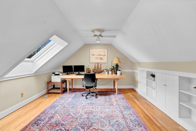 office area featuring wood finished floors, ceiling fan, vaulted ceiling, baseboards, and built in shelves