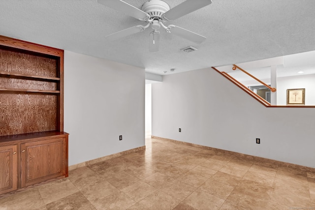 unfurnished living room with ceiling fan, a textured ceiling, and baseboards
