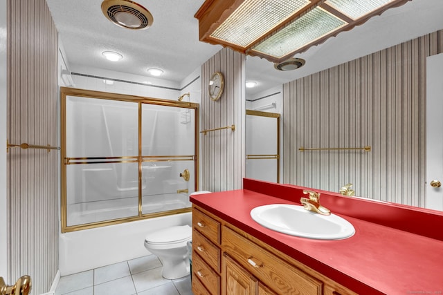 bathroom featuring wallpapered walls, tile patterned floors, toilet, vanity, and enclosed tub / shower combo