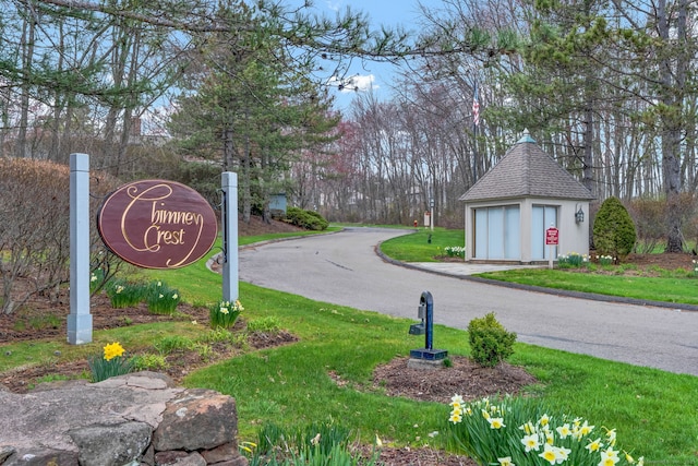 community / neighborhood sign with a detached garage and a lawn