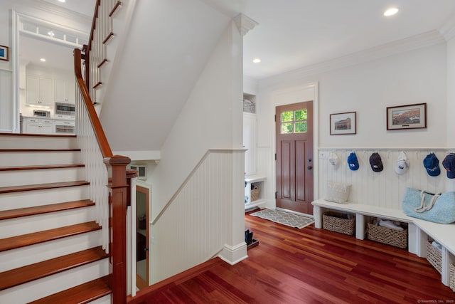 foyer entrance with wood finished floors, stairs, recessed lighting, ornamental molding, and wainscoting