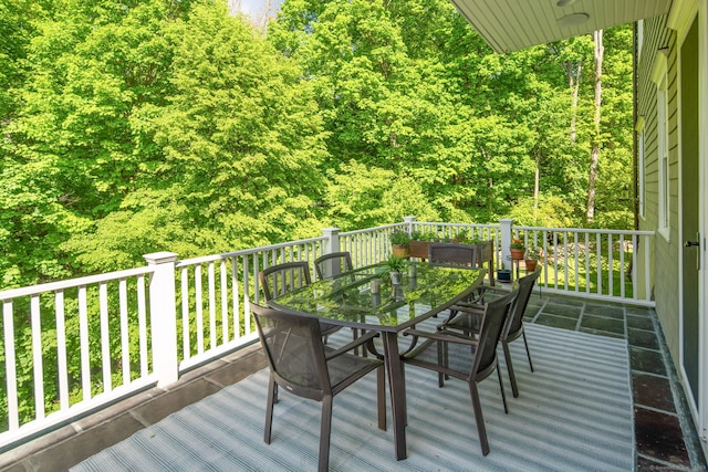 wooden terrace with outdoor dining area and a forest view