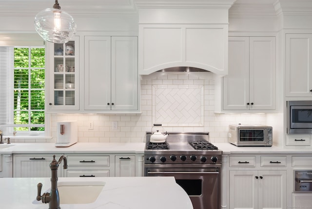 kitchen with stainless steel appliances, white cabinets, a sink, plenty of natural light, and crown molding