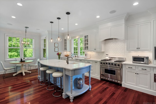 kitchen featuring stainless steel stove, dark wood finished floors, white cabinets, a breakfast bar, and decorative backsplash