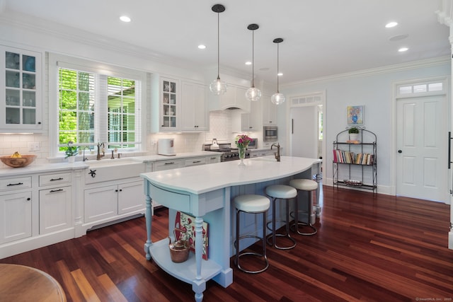kitchen featuring a sink, dark wood-type flooring, light countertops, white cabinetry, and ornamental molding