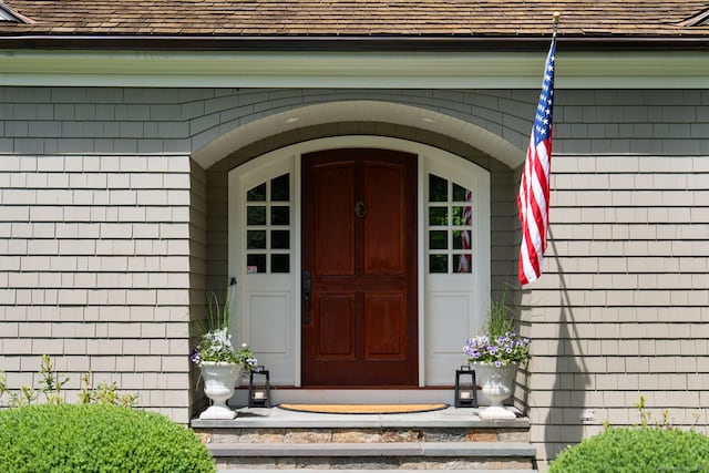 doorway to property featuring roof with shingles
