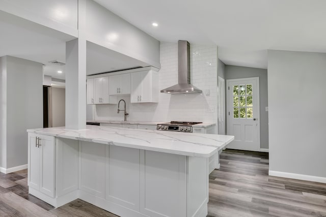 779 New Britain Ave, Rocky Hill, CT 06067 - kitchen with wall chimney exhaust hood, light wood-style flooring, white cabinets, vaulted ceiling, and backsplash
