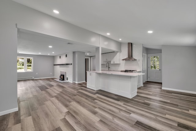 779 New Britain Ave, Rocky Hill, CT 06067 - kitchen featuring wall chimney range hood, light countertops, open floor plan, white cabinetry, and baseboards