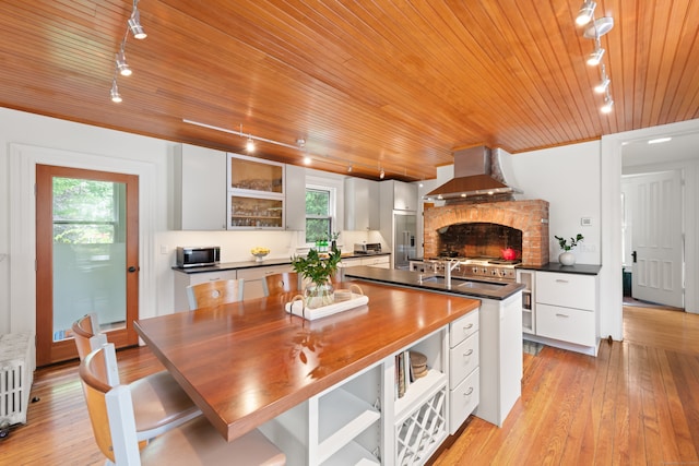 13 Sugar St, Newtown, CT 06470 - kitchen with rail lighting, wall chimney exhaust hood, wood ceiling, white cabinets, and an island with sink