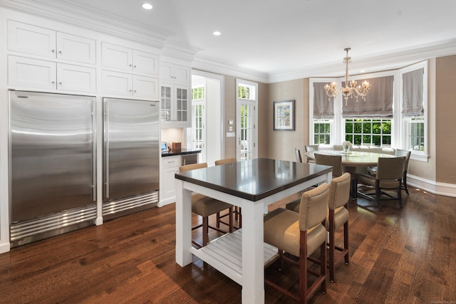 68 Woods End Rd, New Canaan, CT 06840 - kitchen with built in fridge, a chandelier, white cabinets, dark wood-style floors, and ornamental molding
