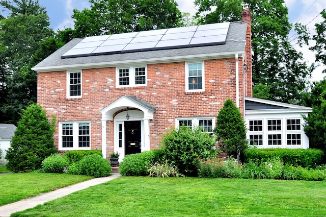 16 Ridgewood Rd, Windsor, CT 06095 - view of front of home with a chimney, a front yard, and roof mounted solar panels