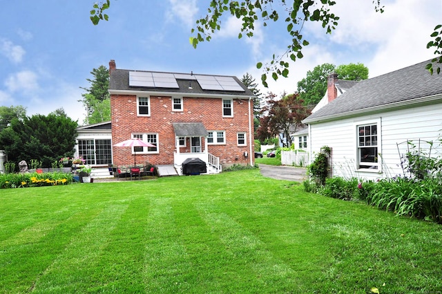 16 Ridgewood Rd, Windsor, CT 06095 - back of property featuring roof mounted solar panels, a lawn, a chimney, and brick siding