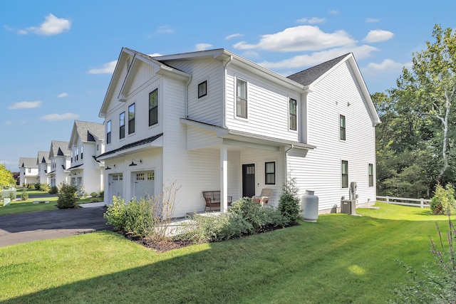 view of front facade with an attached garage, asphalt driveway, central AC, a porch, and a residential view