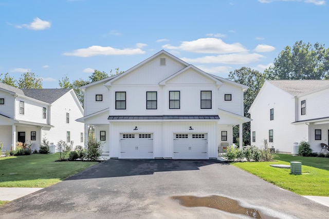 view of front of home featuring board and batten siding, a standing seam roof, asphalt driveway, a garage, and a front yard