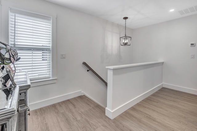 stairway with wood finished floors, a chandelier, and baseboards