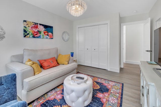 living room with light wood finished floors, a chandelier, and baseboards