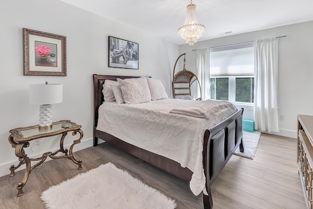 bedroom with a chandelier, light wood-style flooring, and baseboards