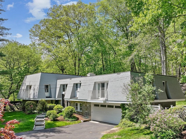20 Mountain Wood Rd, Stamford, CT 06903 - view of front of home with asphalt driveway, an attached garage, a balcony, and stone siding