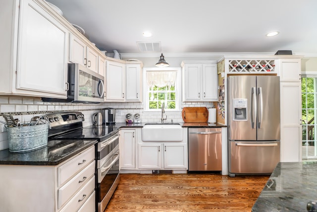 kitchen with stainless steel appliances, a sink, backsplash, white cabinetry, and recessed lighting