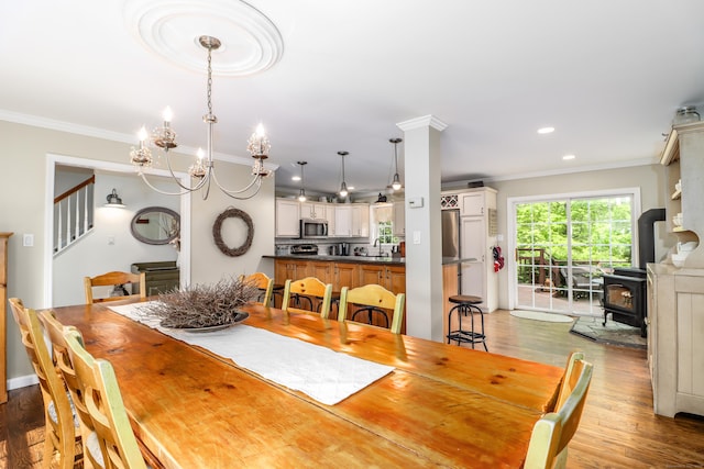 dining room featuring a wood stove, crown molding, light wood-style floors, stairs, and a chandelier