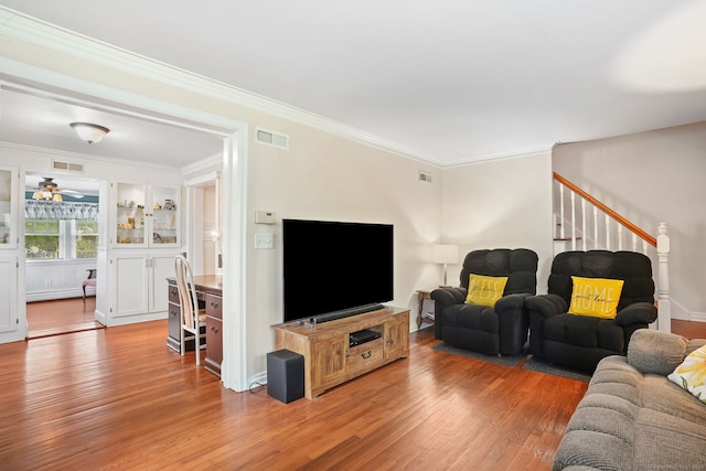 living area with light wood-type flooring, stairway, and crown molding