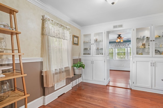 mudroom with ceiling fan, wood finished floors, crown molding, baseboard heating, and baseboards