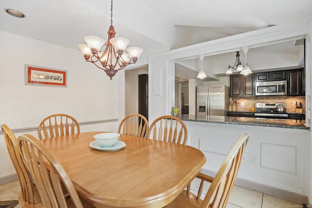 dining room featuring a chandelier, vaulted ceiling, and light tile patterned floors