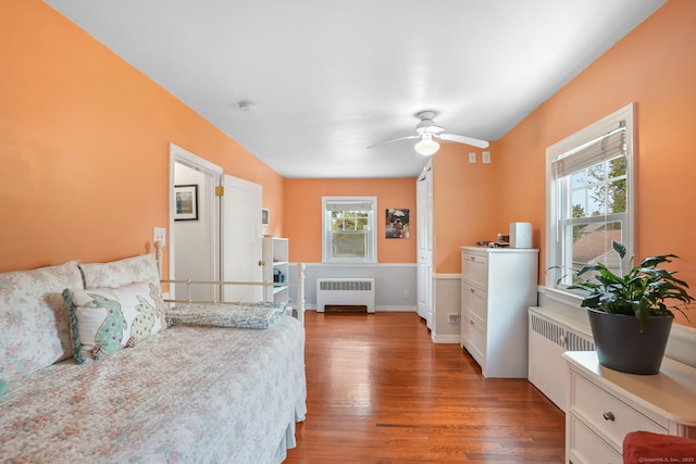 bedroom featuring radiator, wood finished floors, and multiple windows